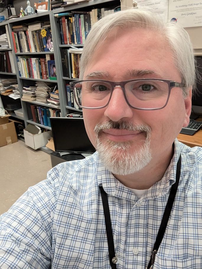 Man with glasses, goatee, and white/gray hair.